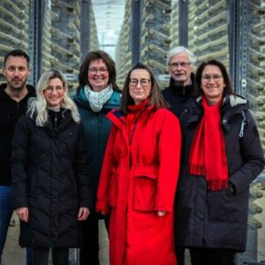 Gruppenbild mit Minister vor dem Glasröhrensystem in der Algenfabrik