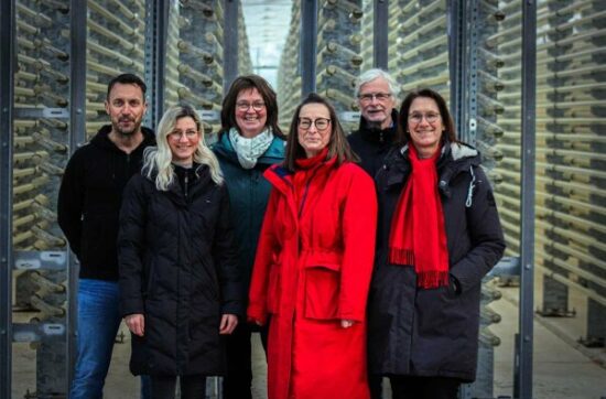 Gruppenbild mit Minister vor dem Glasröhrensystem in der Algenfabrik